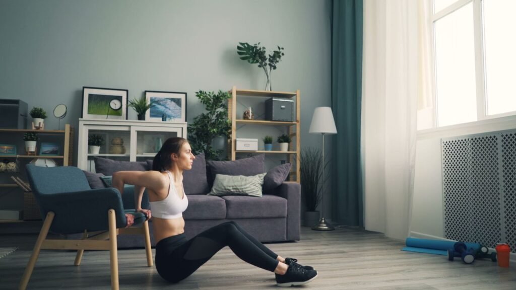 A woman doing a seated exercise with a chair in her living room as a small-space home workout
