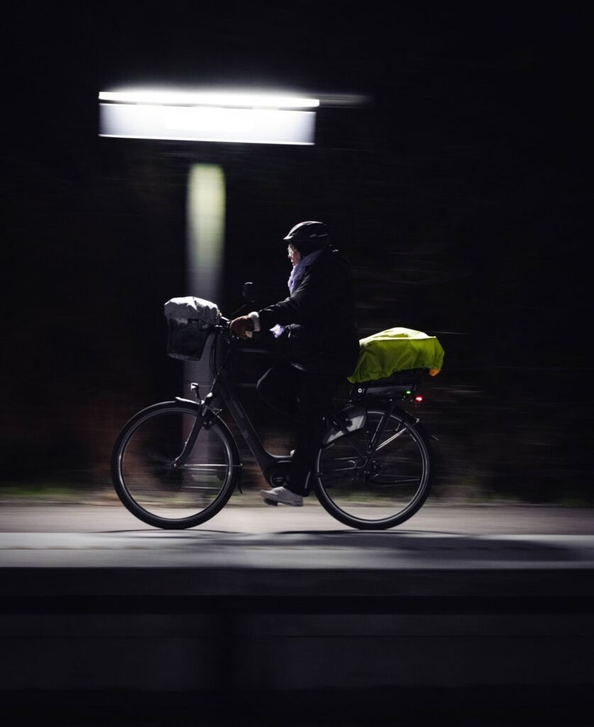 A cyclist riding at night, illuminated by streetlights