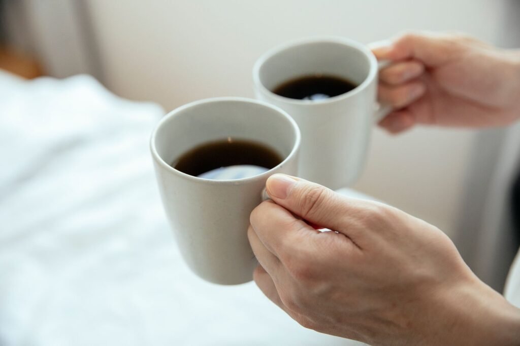 Two hands holding ceramic mugs filled with hot coffee