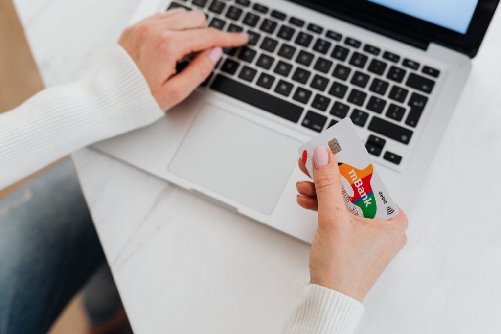 Person completing a secure online checkout holding a bank card next to a laptop